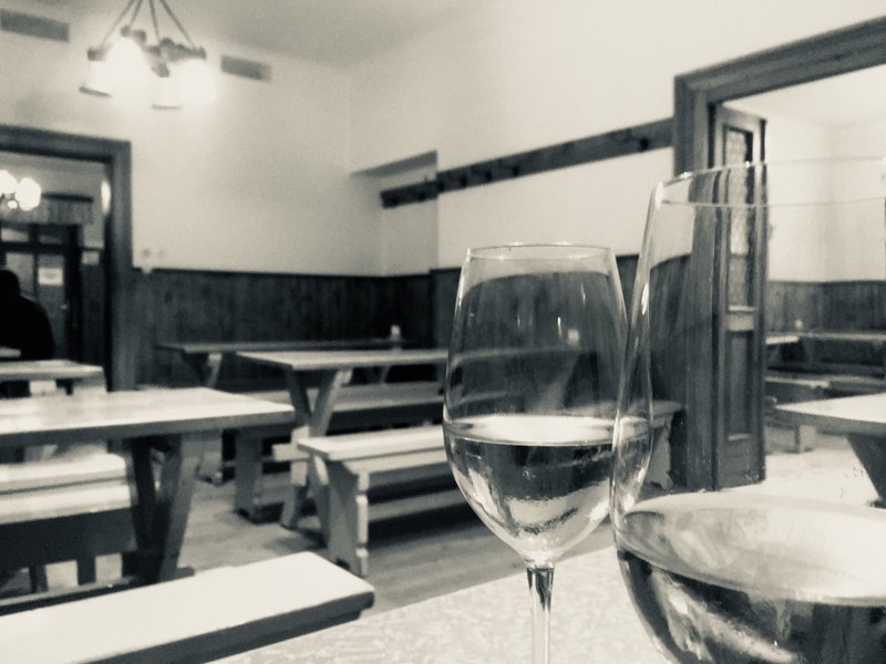 Bänke und Tische beim Heurigen mit Weinglas